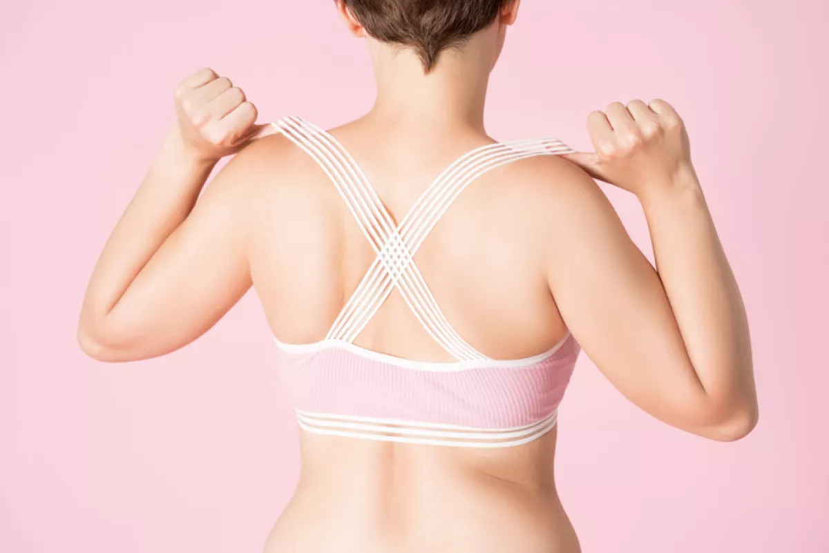 Fit woman in sports bra on pink background
