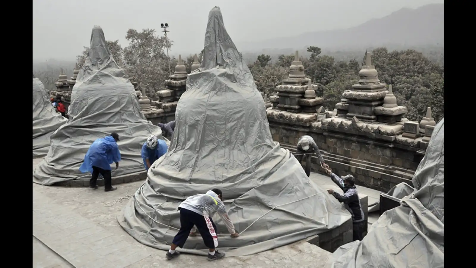 trabajadores cubren de las cenizas el templo de borobudur