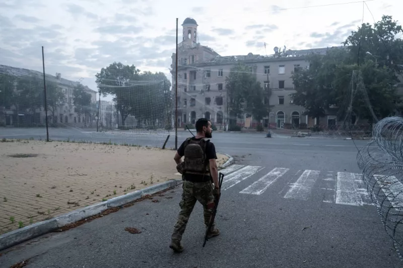 En esta fotografía de folleto tomada el 3 de julio de 2026 y publicada el 5 de julio de 2026 por el servicio de prensa de la 93a Brigada Mecanizada Separada de Kholodnyi Yar de las Fuerzas Terrestres de Ucrania, un servicio de servicio ucraniano camina por una calle cubierta con una red antidrones en Druzhkivka, región de Donetsk, en medio de la invasión rusa de Ucrania.