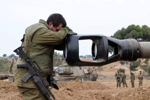 Un soldado israelí descansa su cabeza sobre el cañón de un obús de artillería autopropulsado mientras los soldados israelíes toman posiciones cerca de la frontera con Gaza en el sur de Israel el 9 de octubre de 2023.