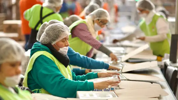 Trabajadoras arman cajas en una línea de producción. 