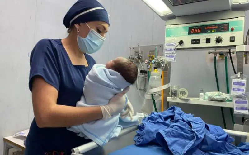 Personal médico sostiene y atiende a un recién nacido junto a equipo especializado en una unidad hospitalaria.