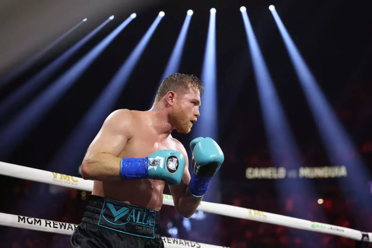 Foto de Saúl Canelo Álvarez sobre el ring con guantes azules y luces sobre él.