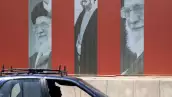 Un coche pasa por delante de una valla publicitaria que muestra fotos del difunto líder supremo de Irán, el ayatolá Ali Khamenei, a lo largo de una calle de Bagdad el 2 de julio de 2026, antes de su funeral en Teherán.