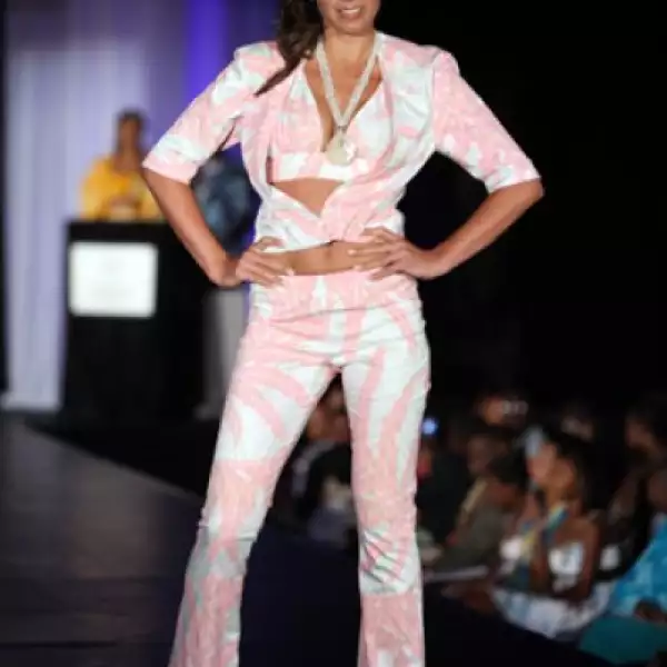 Dragana Atlija, de Serbia, en un conjunto de pantalón, saco y un sexy top, todo en rosa y blanco. El sombrero de copa alta adornado además con grandes flores.