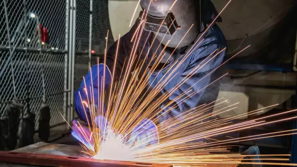 Industrial worker is welding in factory