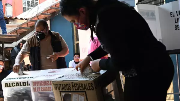 Dos habitantes de Iztapalapa colocan sus votos dentro de las urnas.