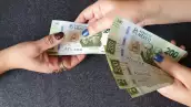 Una persona recibe billetes de 200 pesos.