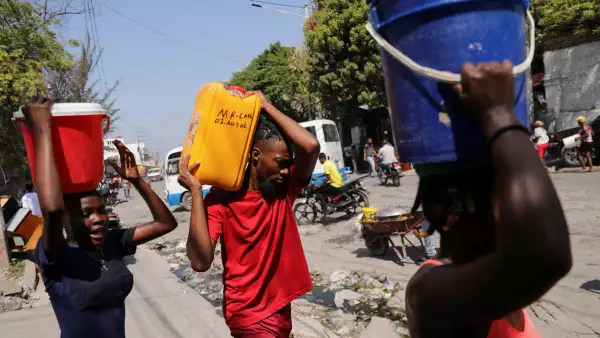 La gente lleva agua recogida en cubos y contenedores a lo largo de una calle después de que el primer ministro de Haití, Ariel Henry, se comprometiera a dimitir después de meses de escalada de la violencia de las pandillas, en Puerto Príncipe, Haití, el 12 de marzo de 2024.