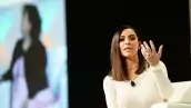 Foto de kim Kardashian en 2016 durante una rueda de prensa, va vestida de blanco y alza su mano izquierda frente a su cara mostrando su anillo de compromiso