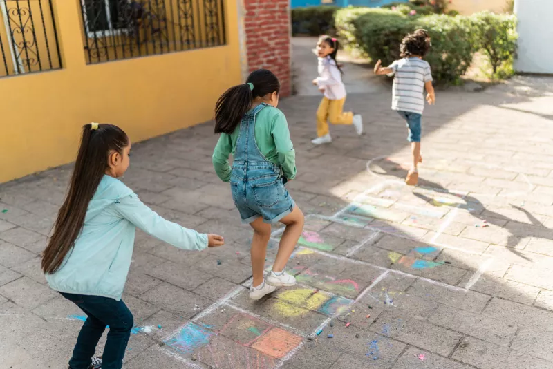 Child friends playing hopscotch outdoors