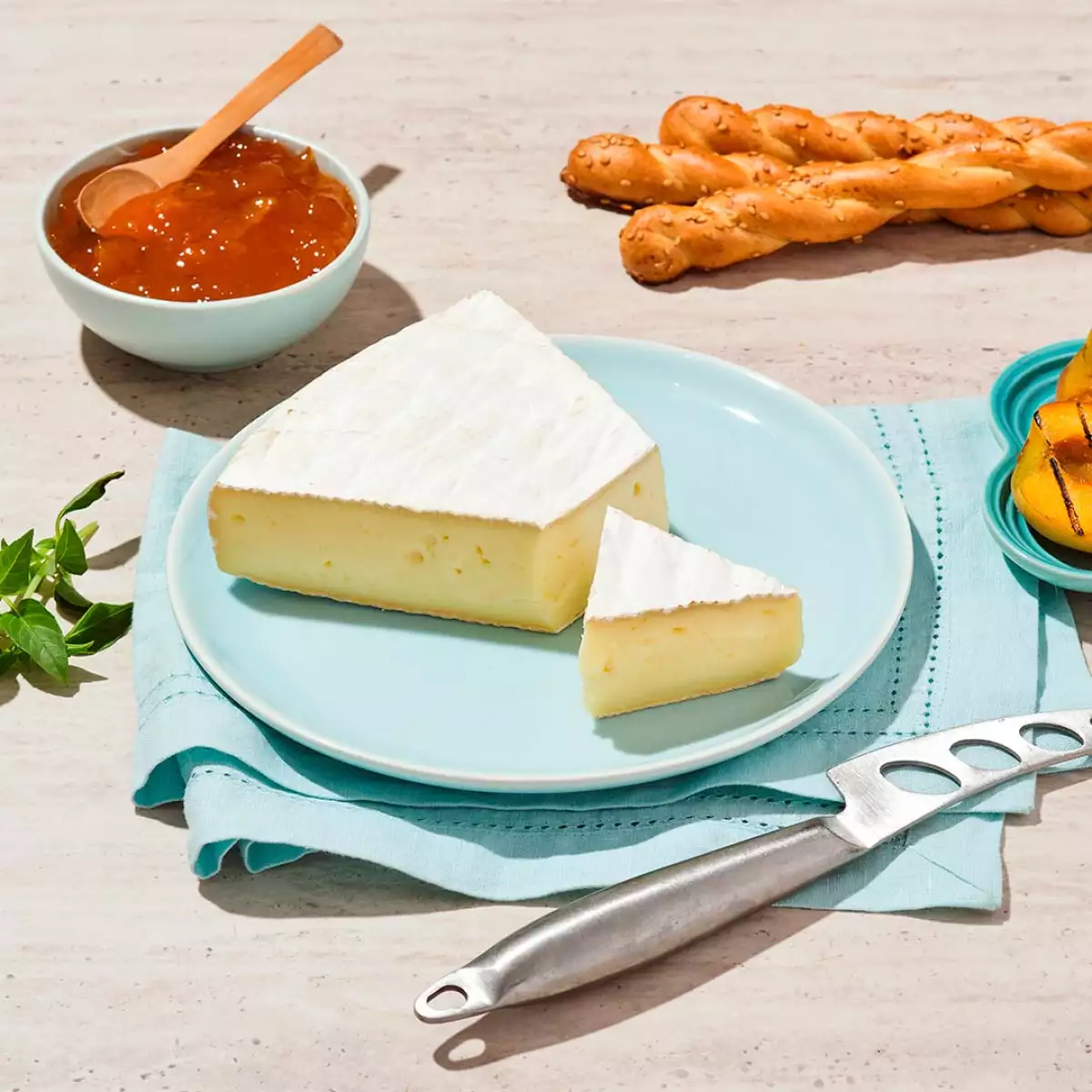 Queso brie en plato azul con mermelada al lado