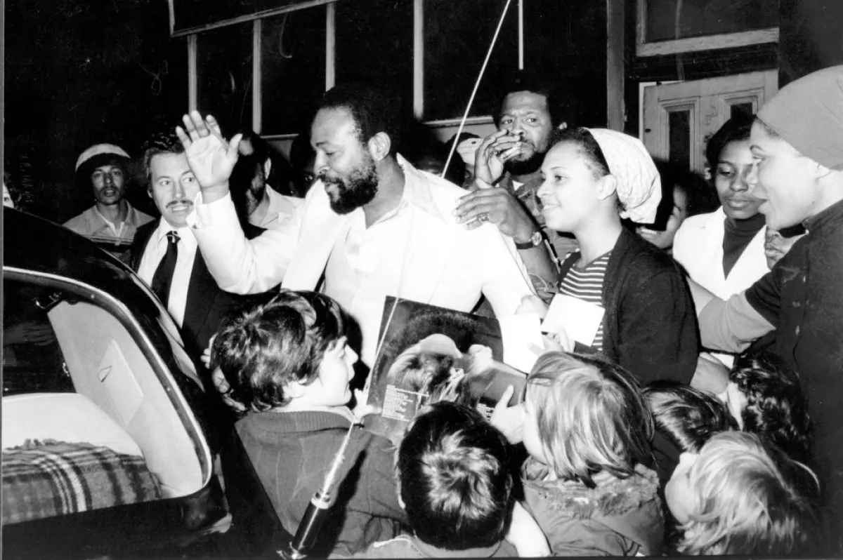 Foto en blanco y negro de Marvin Gaye saliendo de un restaurante y rodeado de fans pidiéndole su autógrafo.