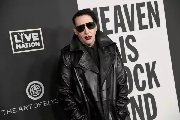 Foto de Brian Warner, conocido como Marilyn Manson, vestido con chaqueta negra de piel, lentes oscuros y boca pintada de rojo a la entrada del evento anual The Art of Elysium, en 2020.
