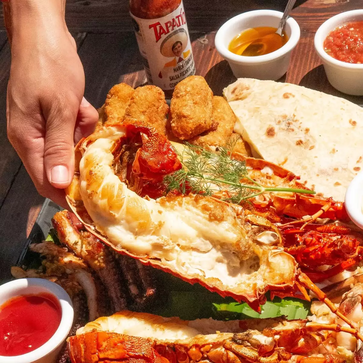 Foto de un platillo de langosta, con tortillas de harina y distintas salsas.