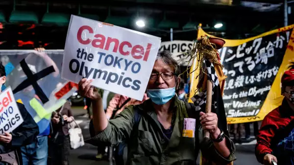 A protester holds a placard that says 'Cancel the Tokyo