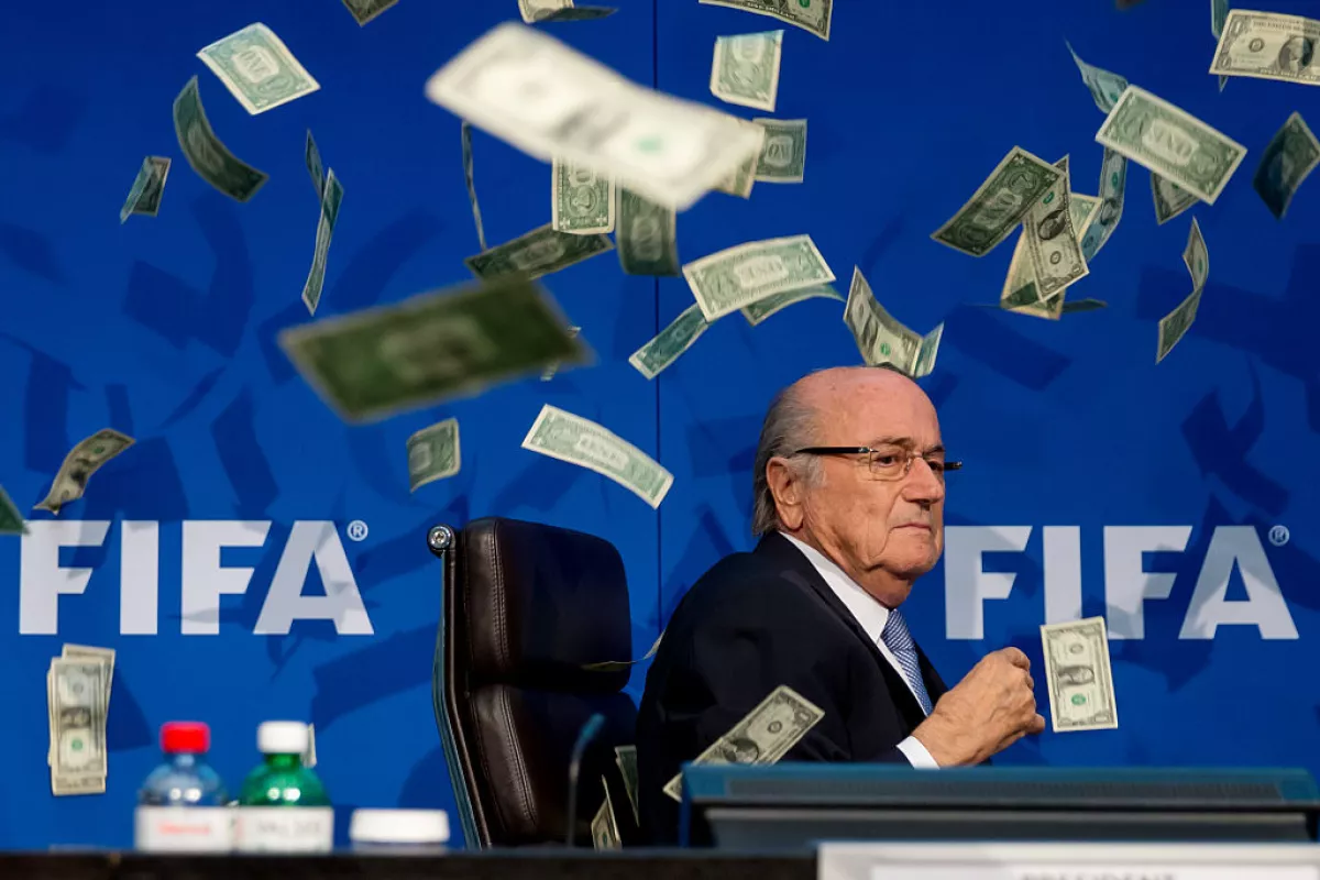 Foto de Joseph Blatter en 2015 con el letrero de la FIFA a su espalda y con decenas de billetes de un dolar volando a su alrededor.