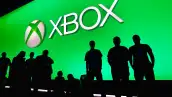 Asistentes a panel de Xbox posan frente al logo de la marca.