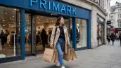 Una mujer con múltiples bolsas cafés de compras sale de una tienda de Primark.