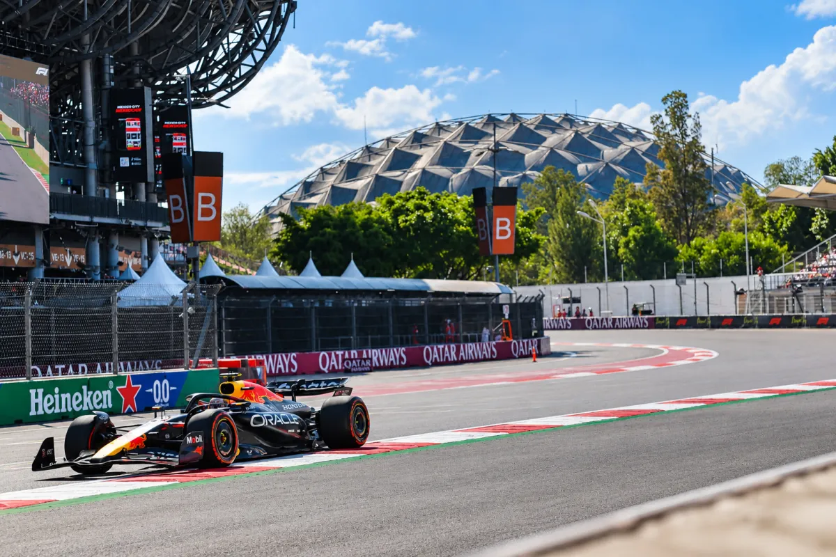 Auto de Fórmula 1 de Red Bull en una curva del Autódromo Hermanos Rodríguez, con el estadio y las gradas al fondo.
