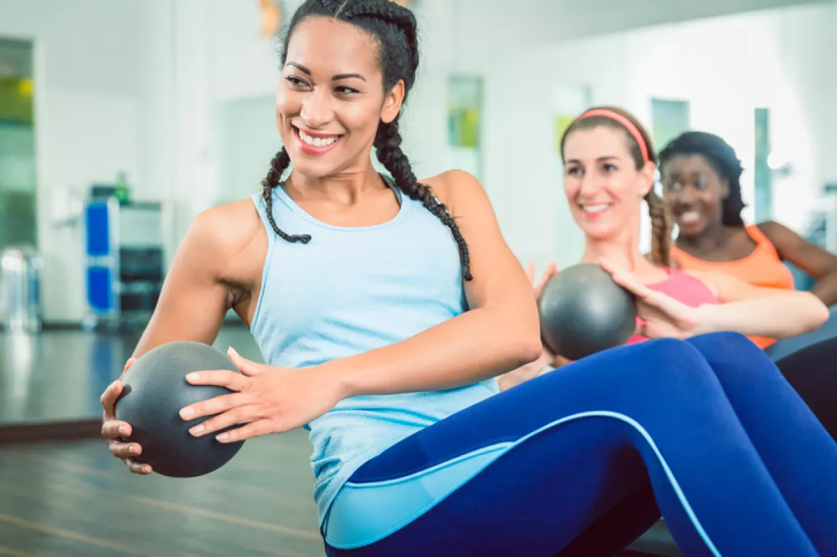Beautiful woman exercising Russian twist with med ball for strong abs at the gym