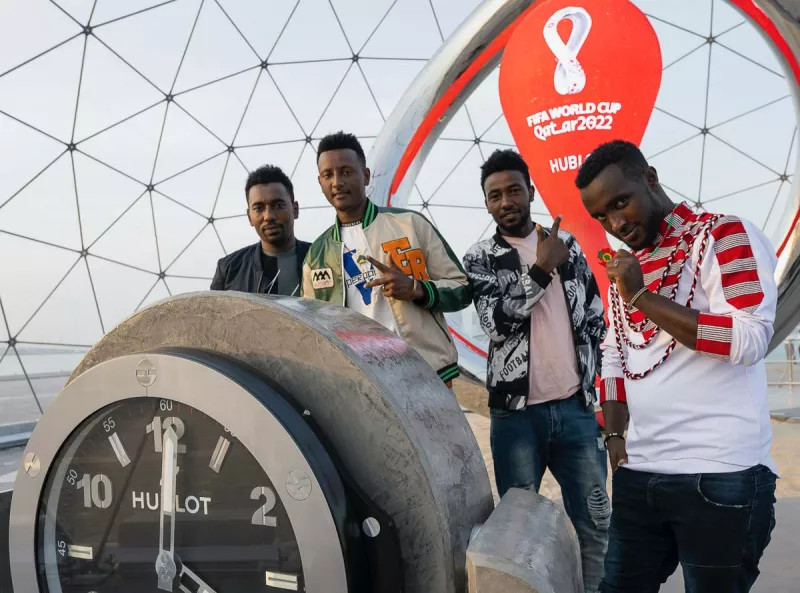 (Migrantes posan en el reloj de la cuenta regresiva para la Copa Mundial, Qatar 2022)