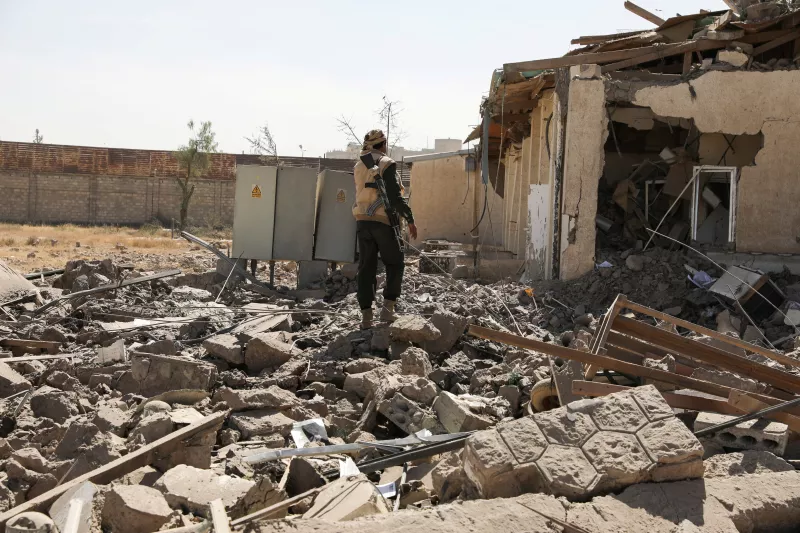 Un guardia de seguridad inspecciona el sitio de un ataque aéreo de Arabia Saudí contra una estación de telecomunicaciones en Sanaa, Yemen. 