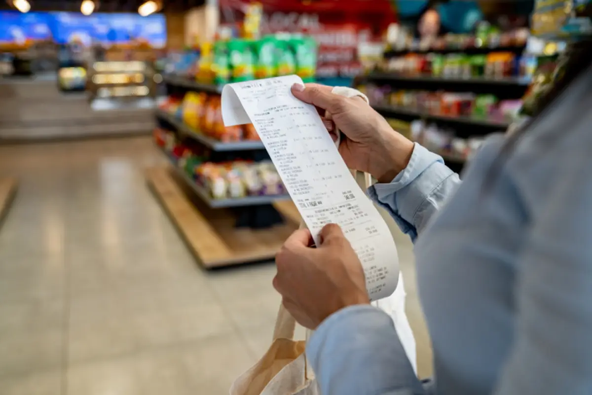 Imagen de mujer viendo y revisando su ticket de compra en un supermercado 