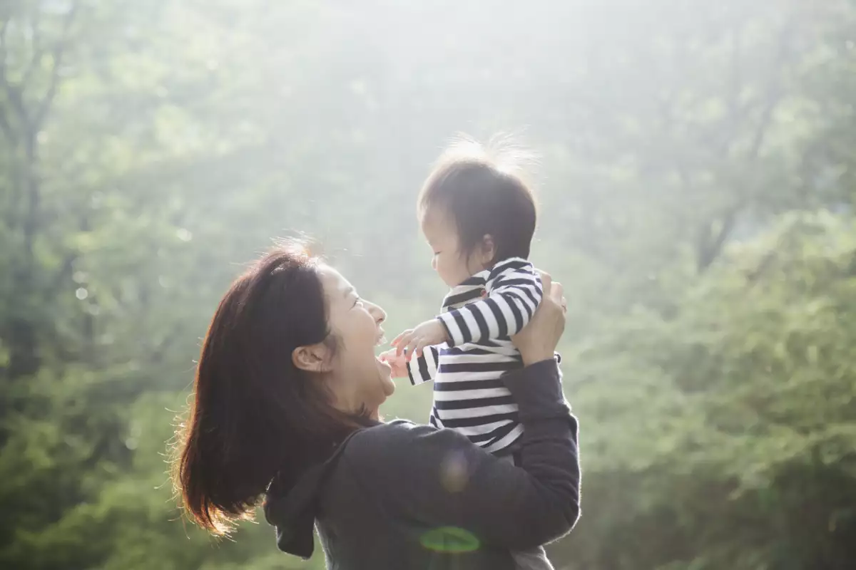 Una madre asiática carga a su bebé niña en una montaña. 