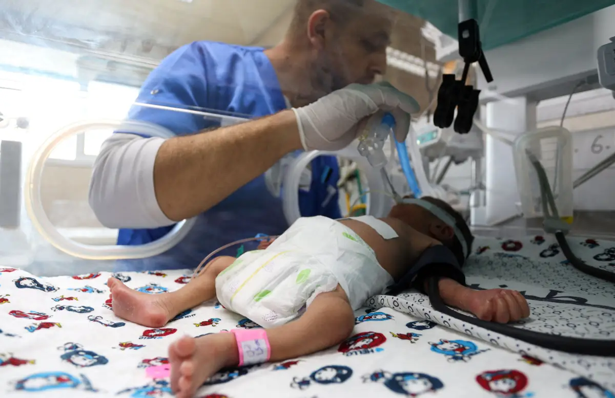 Un trabajador médico ayuda a un bebé palestino prematuro que yace en una incubadora en la sala de maternidad del Hospital Shifa, que según los funcionarios de salud está a punto de cerrarse a medida que se queda sin combustible y energía, mientras continúa el conflicto entre Israel y el grupo islamista palestino Hamas, en la ciudad de Gaza el 22 de octubre de 2023.