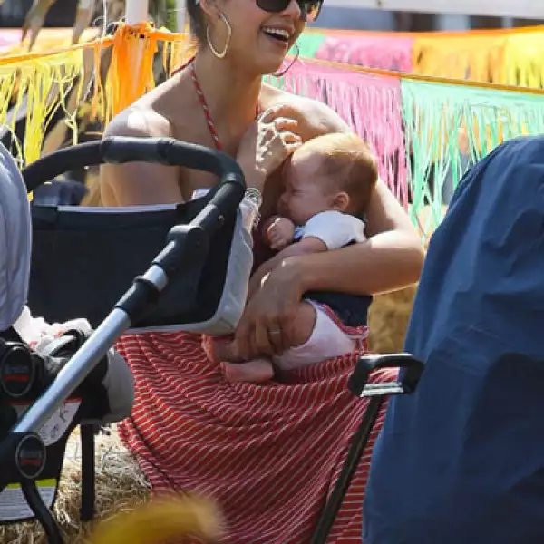Jessica Alba descansa un momento con su hija recién nacida Haven Garner, mientras su esposo Cash Warren y su hija mayor Honor pasean por el huerto.