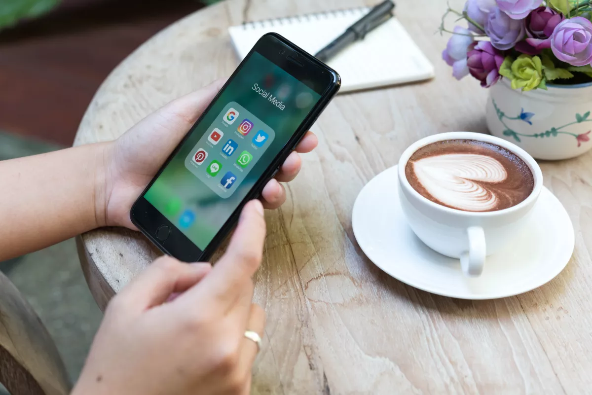 CHIANG MAI, THAILAND - NOVEMBER 14th, 2016: Hands using Iphone7 Plus jet black color with icons of social media on screen in coffee shop with latte art