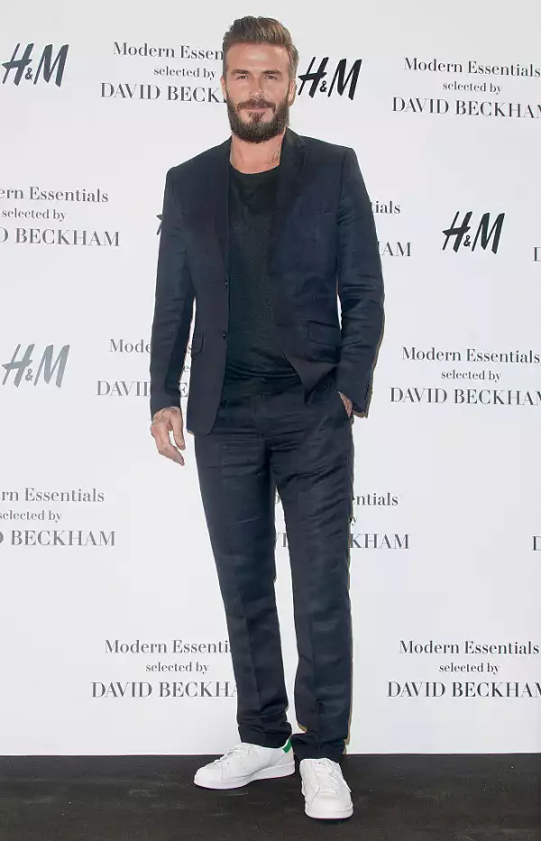 Foto de David Beckham con traje oscuro y tenis blancos en la presentación de su colección para H&M en 2015.
