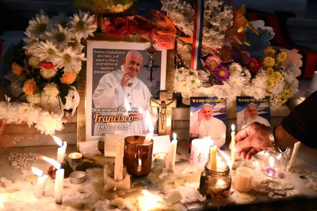 Velas y flores se colocan junto a las imágenes del difunto Papa Francisco en la entrada de la Catedral de Buenos Aires el 21 de abril de 2025.