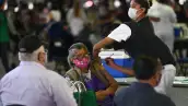 Una adulta mayor es vacunada contra el Covid-19 dentro del Palacio de los Deportes.