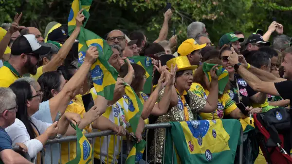 Personas con banderas de Brasil tras una valla en espera de que pasen los candidatos a la presidencia de Brasil.