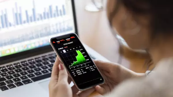 Young finance expert  analyzing financial charts on smart phone
