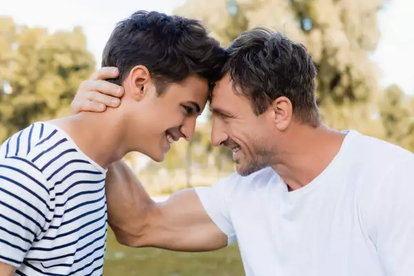 Lado,vista,de,alegre,padre,e,adolescente,hijo,mirando