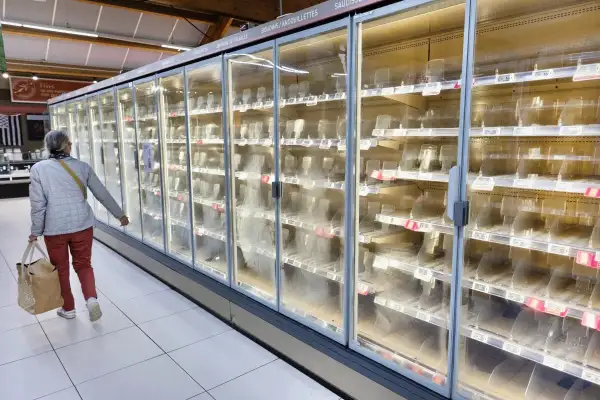 Una persona aparece caminando por los pasillos de un supermercado y se muestran los refrigeradores vacíos tras el ciberataque en Francia. 
