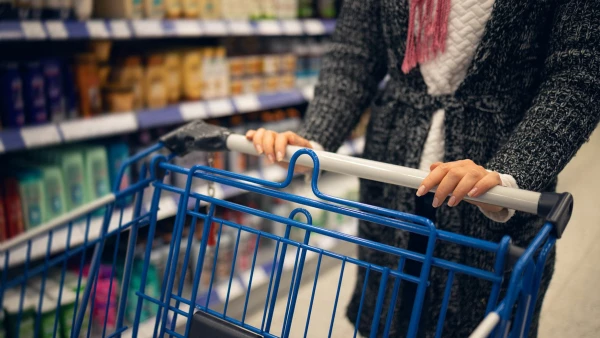 (Mujer lleva un carrito semivacío en un supermercado)