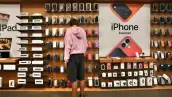 Persona parada frente a una estantería de Apple eligiendo accesorios para iPhone en una tienda de la marca en Manhattan, Nueva York.