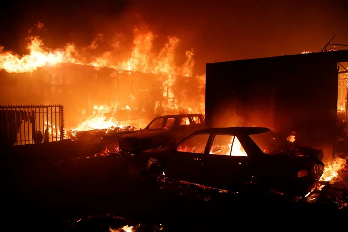 Los vehículos y las casas se queman durante un incendio en Viña del Mar, Chile, el 2 de febrero de 2024. Una enorme nube en forma de hongos de humo cuelga sobre las zonas turísticas del centro de Chile, incluyendo Viña del Mar y Valparaíso, donde se estalló un incendio forestal el viernes, amenazando a cientos de hogares y forzando la evacuación de los residentes.