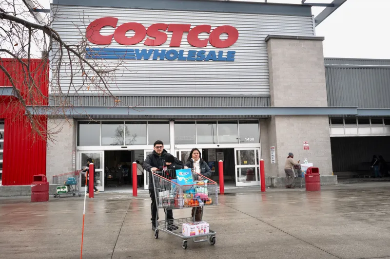 Clientes caminando con un carrito lleno fuera de Costco.