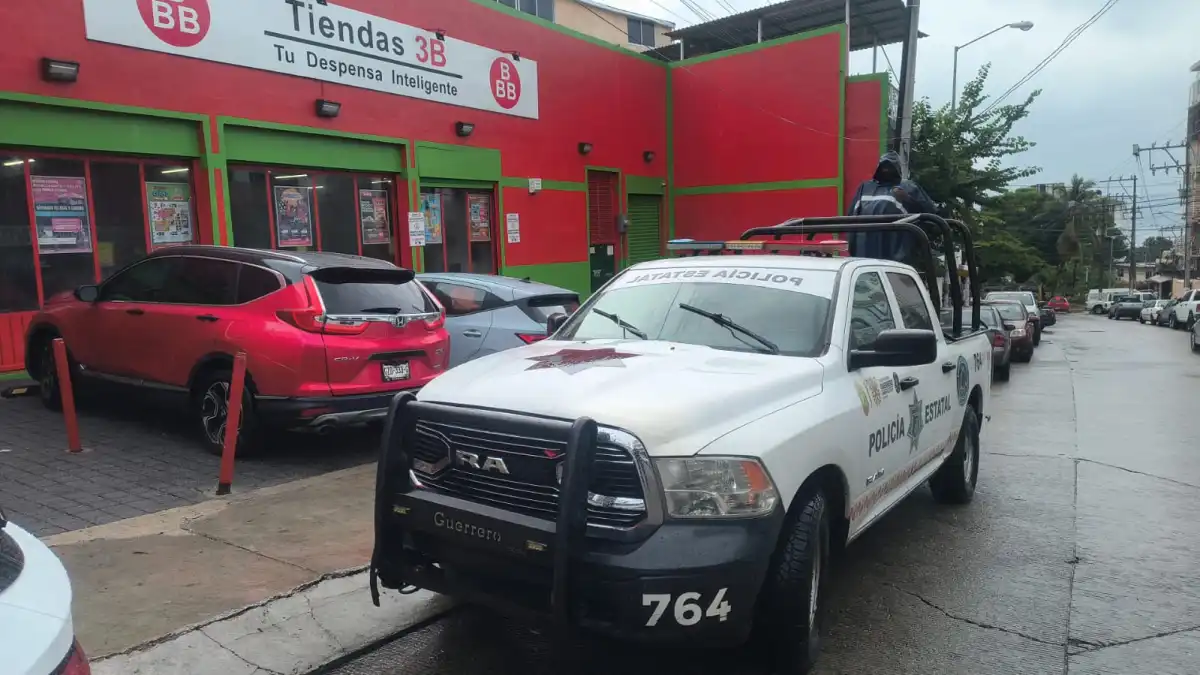 Una camioneta de la patrulla estatal afuera de una tienda 3B de fachada roja y verde. Afuera hay un coche rojo y blanco estacionados.jpeg
