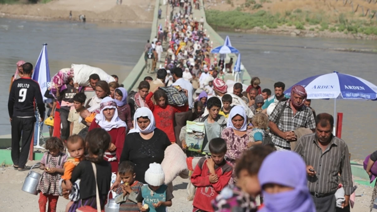 Iraquíes desplazados de la comunidad yazidí cruzan la frontera de Siria con Iraq, acechados por el grupo extremista ISIS