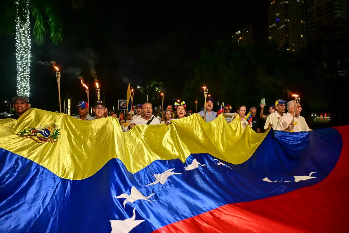 Manifestantes que llevan antorchas y una marcha de la bandera venezolana en apoyo a la líder de la oposición venezolana María Corina Machado en la ciudad de Panamá el 6 de diciembre de 2025. Machado, que vive escondida en su país, ha confirmado que viajará a Oslo para recibir su Premio Nobel de la Paz, dijo el jefe del Instituto Nobel a la AFP el 6 de diciembre.