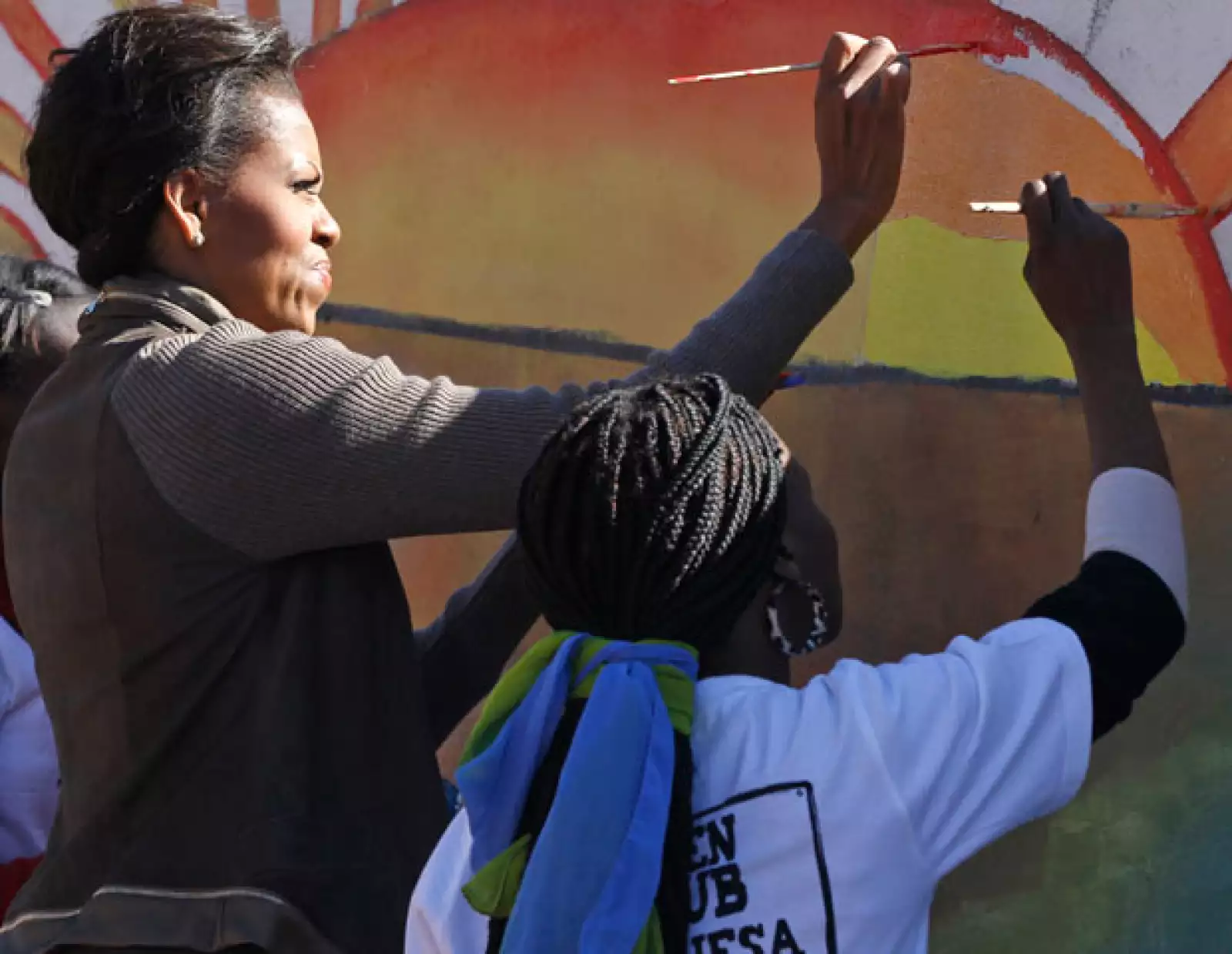 Michelle e integrantes de su familia que la acompañan ayudaron a pintar un mural en la pared de una nueva instalación que se está construyendo en Botsuana.