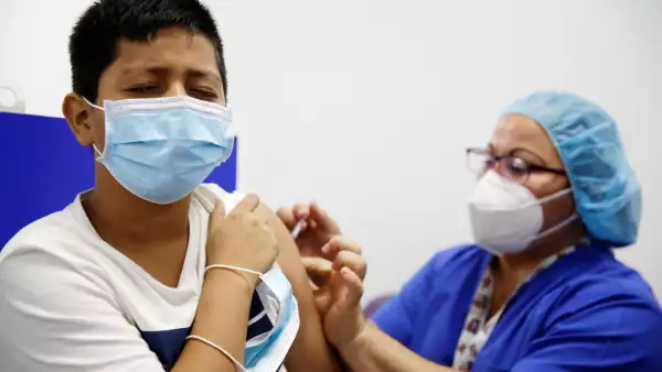 Estas son las fechas y las sedes para que los niños reciban la vacuna covid en CDMX. (Mujer del personal de salud vacunando a un niño contra covid).