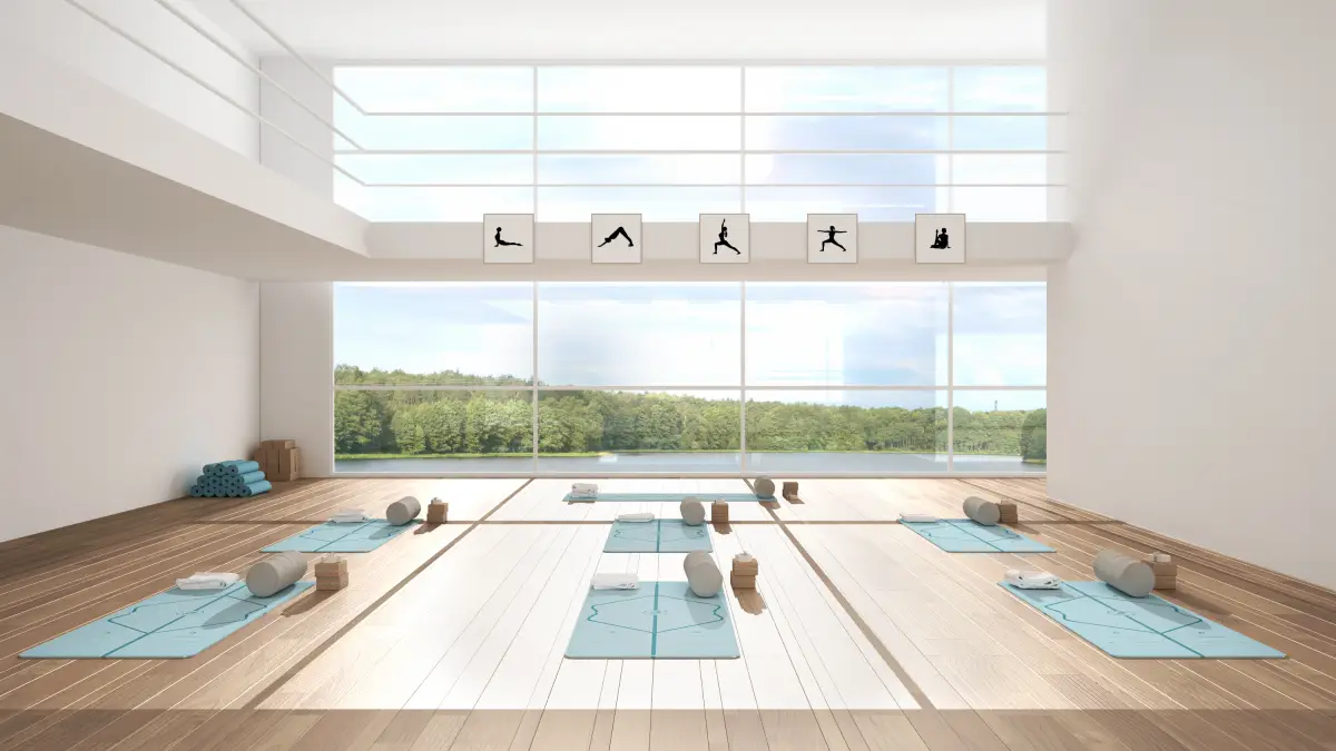 Estudio de yoga vacío con tapetes azules y ventanas grandes.