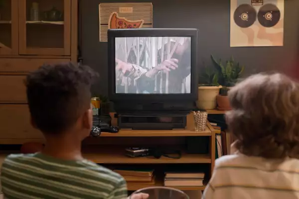 Back,View,Of,Two,Kids,Sitting,On,Floor,Watching,Tv